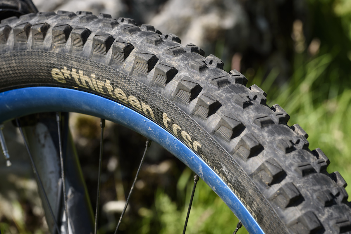 Joining e*thirteen’s ever-expanding product line-up last year, the e*thirteen TRSr is intended to slot in between lightweight cross-country tyres and super-burly downhill tyres – in the words of Goldilocks, not too hot and not too cold, but juuuust right. Or to put it another way, a regular trail tyre for everyday use. That might be doing these tyres a slight disservice though, as they’ve performed brilliantly throughout the test and are more than ‘just right’. Available in 27.5in and 29in options, with folding bead, reinforced sidewalls, reinforced pinch flat zones and enduro casing, they tip the scales at 918g (27.5in, 900g quoted) and are designed to pop up tubeless with just a track pump and a scoop of sealant. True to their word they went up without needing a compressor on every rim we tried, every time. Available in two compounds (Race or Plus), we’ve been riding the softer, grippier, Race compound which is made up of 70a rubber at the base, 42a in the centre, and a 40a for the side knobs. Given how soft the tyres feel under the thumbnail, they rolled along really well, and were only a bit draggy on long road sections. Once up to speed and onto the fun stuff though, that drag wasn’t noticeable, and the payoff was that they provided ample grip for climbing, especially when faced with things like slanted wet rock or rooty madness sections. If outright climbing traction isn’t required, you might want to consider either the harder compound TRS+, or a modern semi-slick such as the Maxxis Minion SS. The sidewalls felt really supportive and I often found myself running less pressure than I thought – sometimes as low as 22/24 psi front/rear, with very little tyre body roll, while on rockier Lakeland descents we upped the pressures slightly. Even if you go fast enough to drift, the traction is super-reliable except on very loose marbley surfaces, where we have yet to find a tyre that works perfectly. With a carefully shaped and siped tread pattern reminiscent of a Magic Mary, they offer great grip in mud and slop too, with lots of clearance, and the rubber was soft and edgy enough to keep things under control for braking when the going got loose. On the first off-road descent of the first ride on the tyre, we managed to put a hole in the rear that needed two tubeless plugs to seal. However, after that, it has been puncture and trouble free for over a year, even hitting long rocky Lakeland descents where we could feel the tyres bottoming out and carbon rims impacting on the ground below. As such, the pair of tyres on test has done a hard week of descending in the Pyrenees, many rides around Calderdale, trips to Peebles, and finally they’ve ended up here in the Lakes. They’ve not been ridden every day as they’ve been on a ‘weekends and trips’ bike, but we reckon they’ve done a good few hundred miles. While the rear is worn, they are looking surprisingly good for their age, and for the amount of riding time we’ve put into them in relation to the level of grip they return, the wear has been excellent and as they’ve worn the performance hasn’t fallen away as dramatically as it has with other tyres on test. Overall There is no denying that at £59.95, they’re at the upper-mid end of the price spectrum, but we’ve really got on well with these tyres, If you think of them as track day tyres for your sports car, it’s well worth getting a pair for racing and Alps trips and maybe use something else for day-to-day riding.