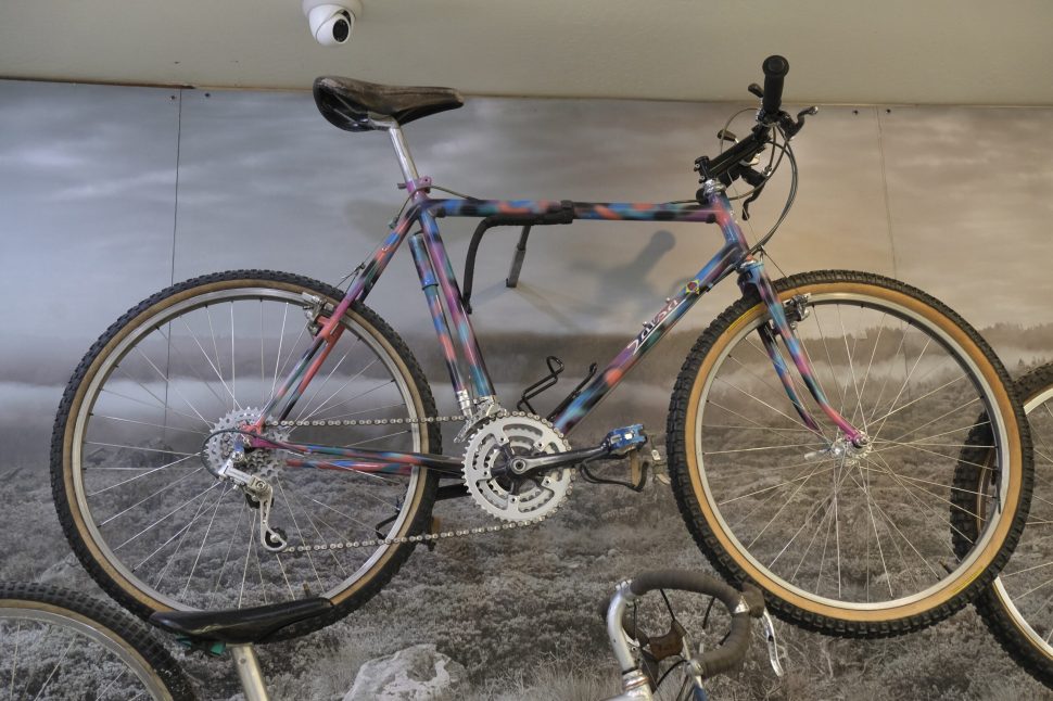 A colorful vintage mountain bike displayed against a scenic backdrop, showcasing its unique paint job and design features.