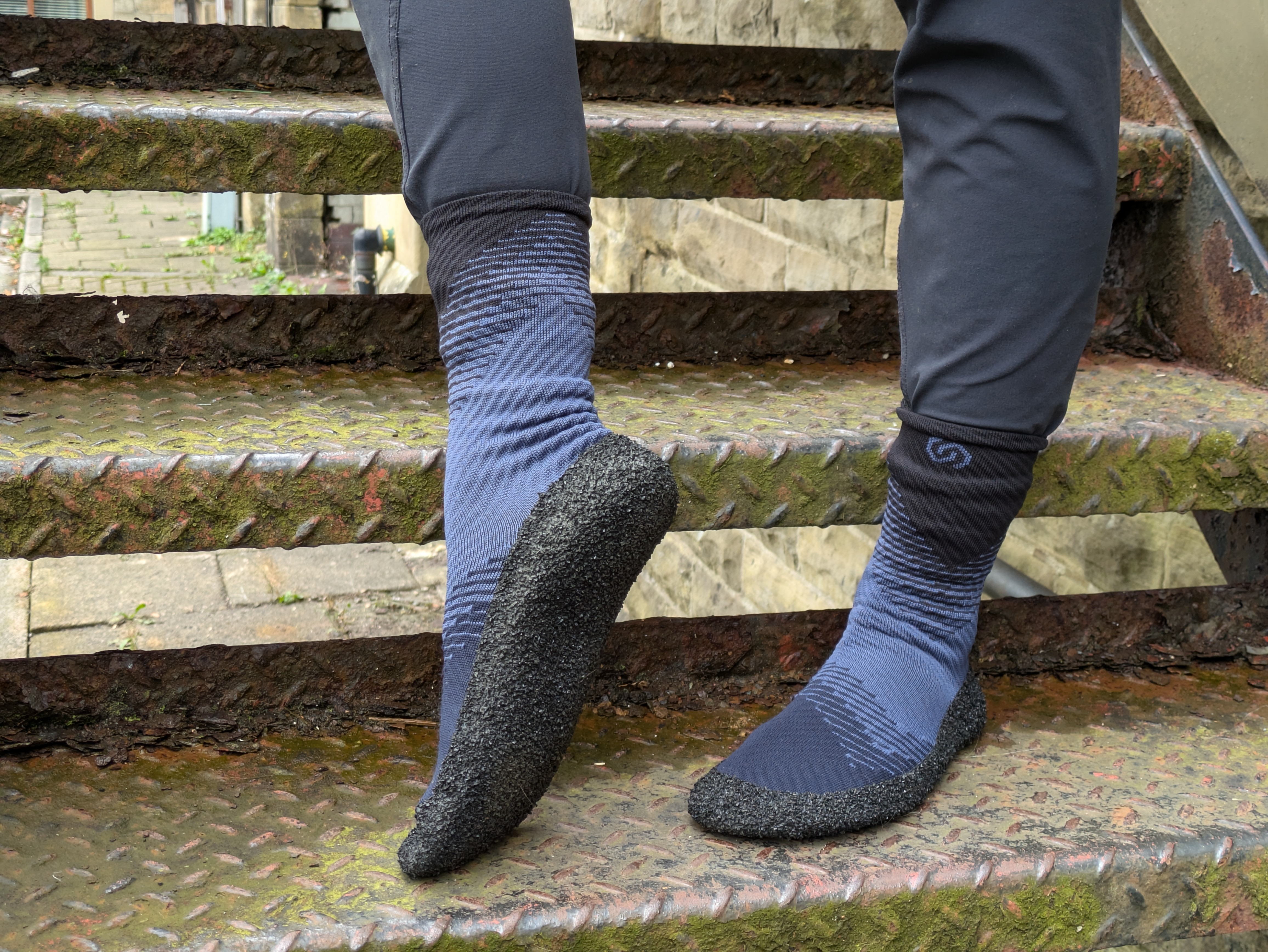 Close-up of a person standing on metal stairs, wearing light-weight, multi-textured socks designed for outdoor or water activities.