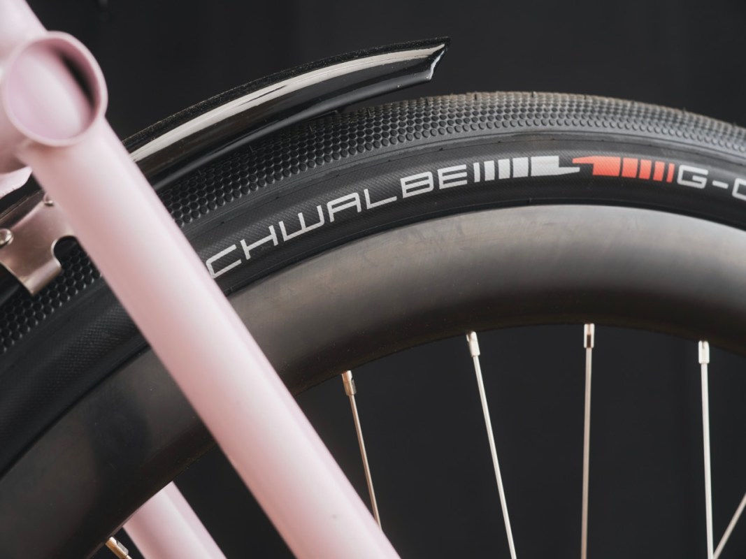 Close-up of a bicycle tire with a 'Schwalbe G-One' label and a pink bicycle frame partially visible.