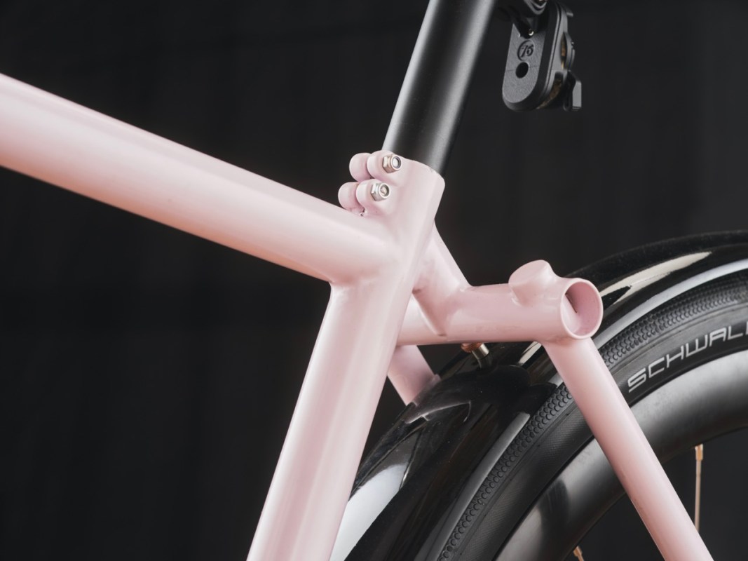 Close-up of a pink bicycle frame showing the bottom bracket area and tire.