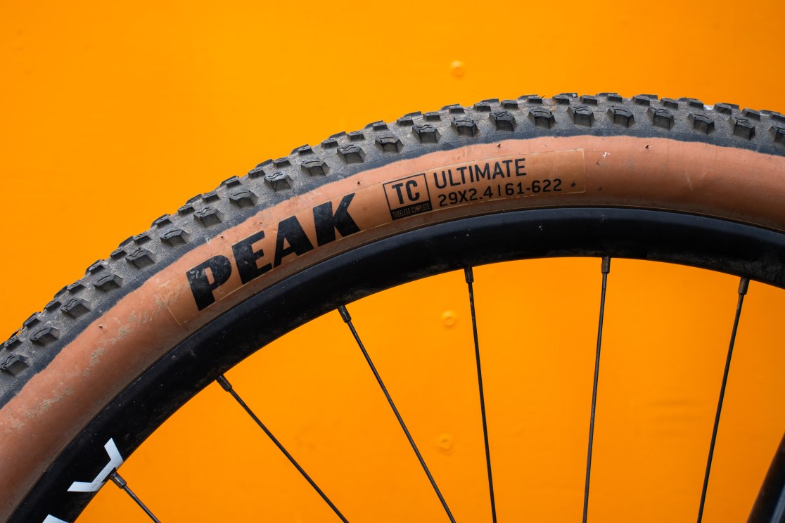 Close-up of a Goodyear Peak Ultimate mountain bike tire, labeled '29X2.4' on an orange background.