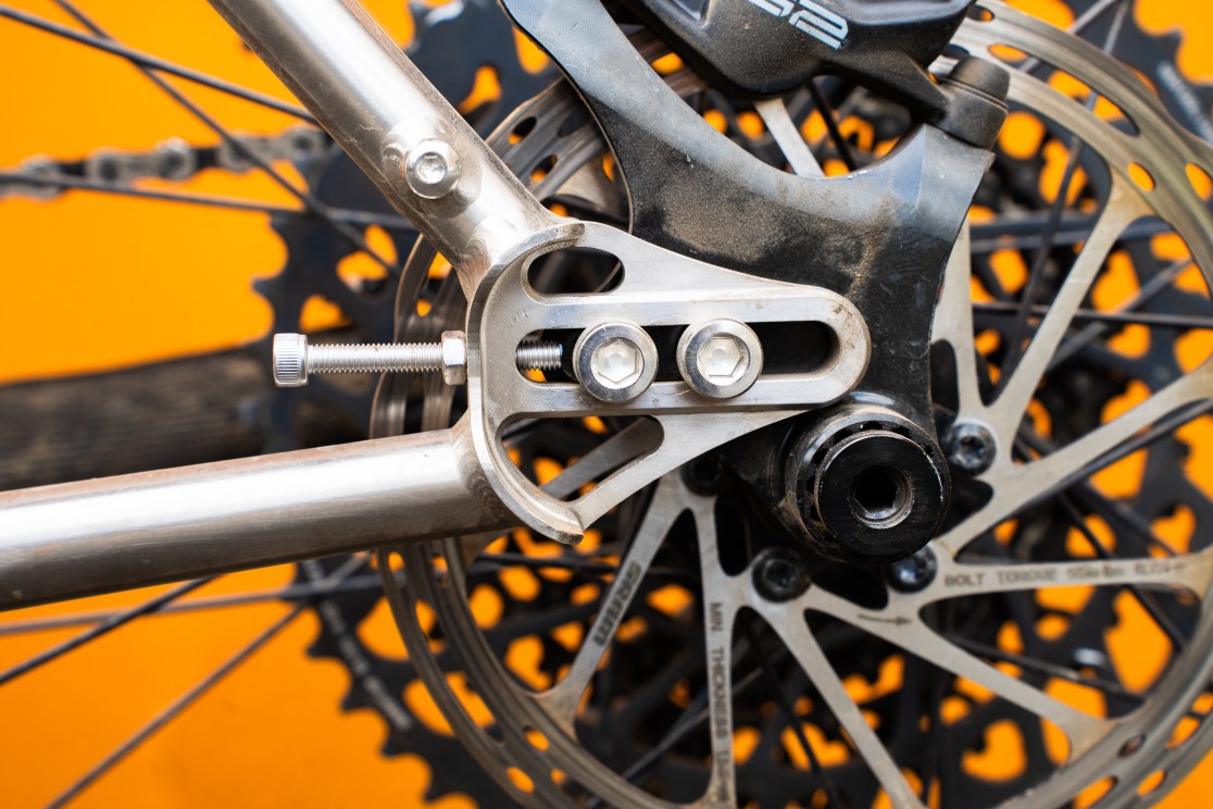 Close-up of the rear dropout and disc brake setup on a Sonder Broken Road Ti mountain bike, showcasing the adjustable sliding dropout design.