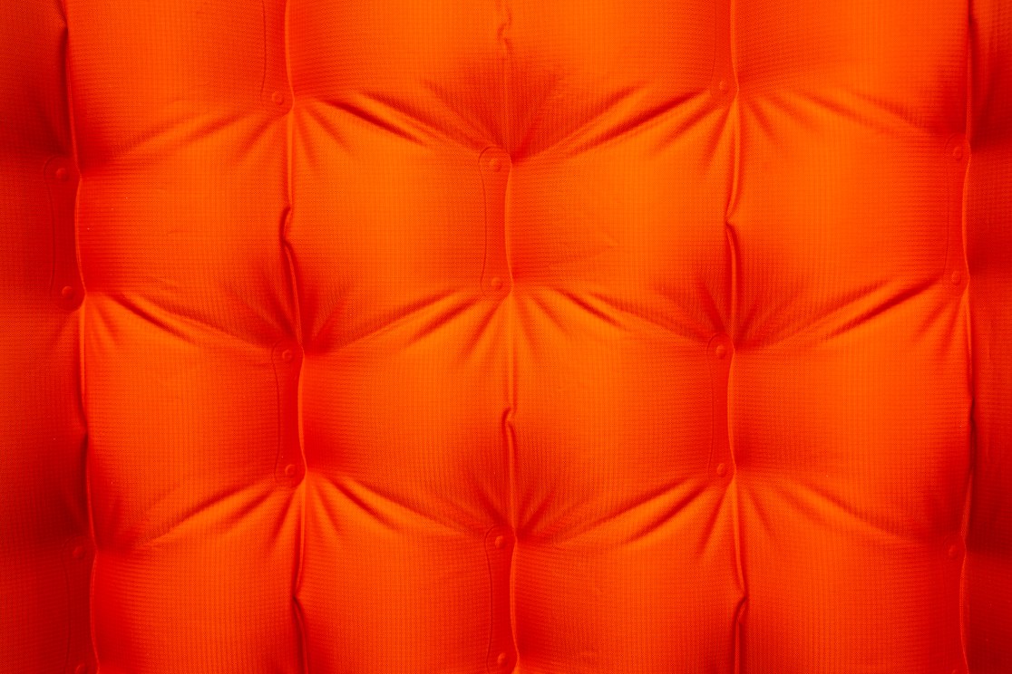 Close-up of an orange insulated sleeping mat with a quilted texture.