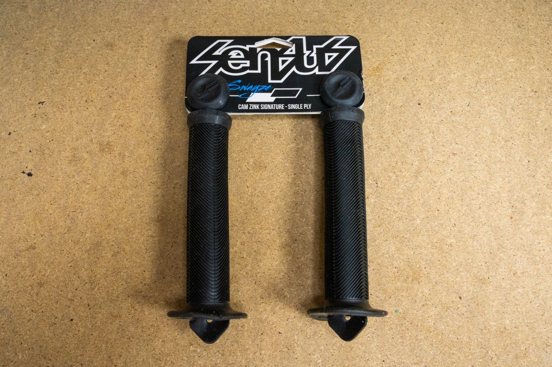 Sensus Swyaze Single Ply Grips displayed on a wooden surface, featuring a textured black surface and flanged ends.