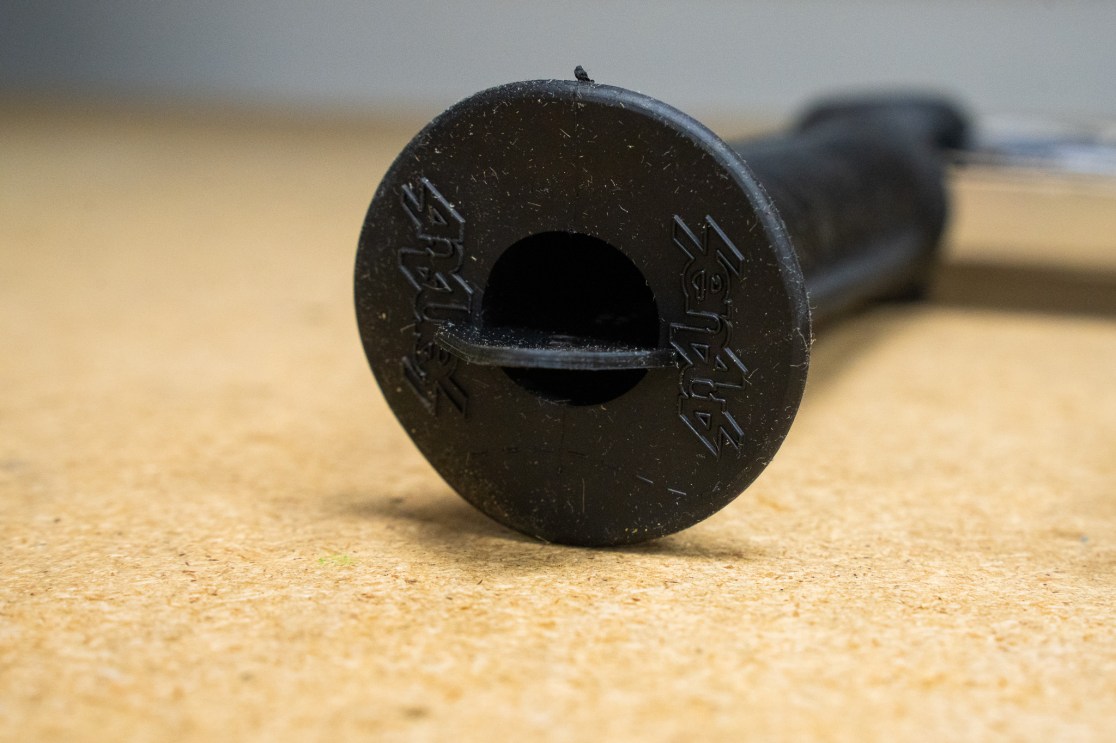 Close-up of a bicycle grip end featuring a textured surface and a hole for installation.