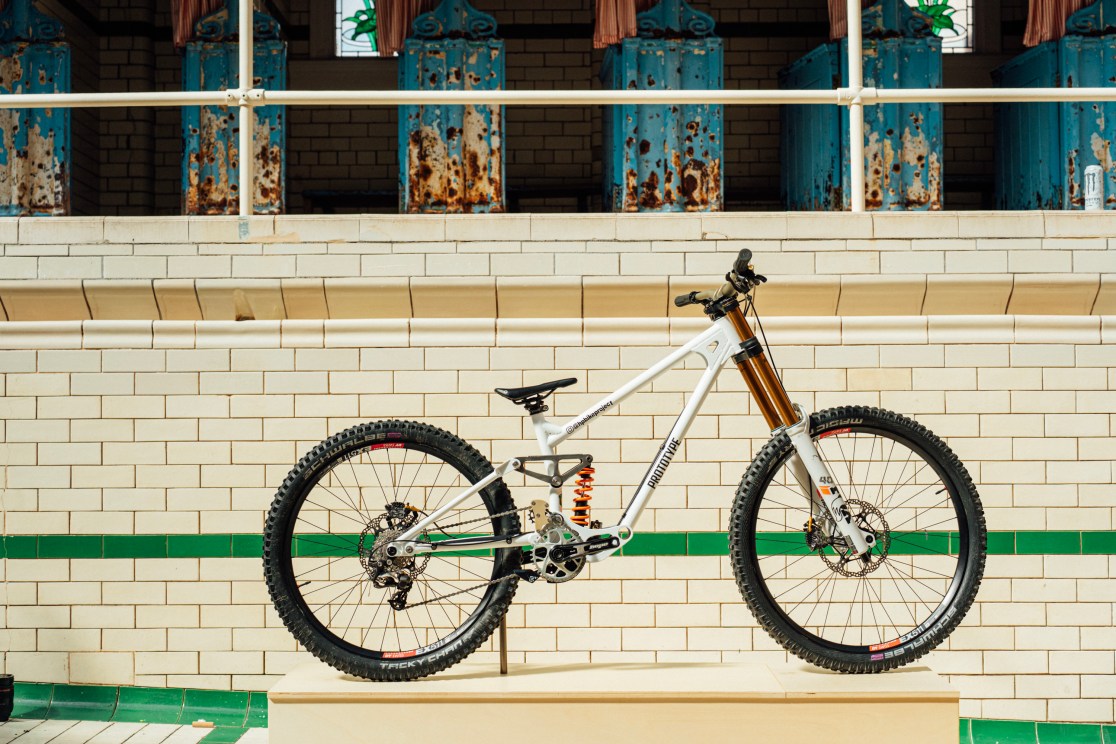 A custom-built downhill bike displayed on a pedestal, showcasing its unique steel frame and advanced suspension system.