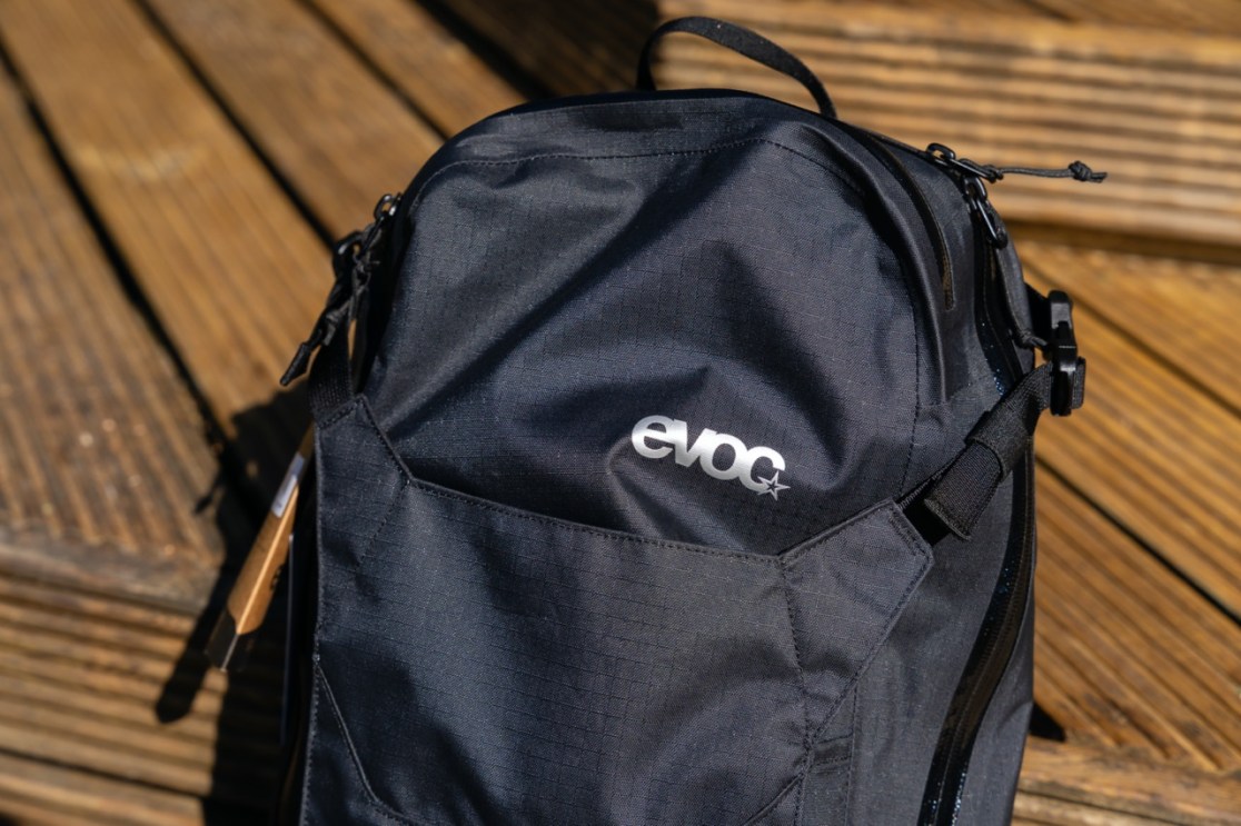 Close-up view of an Evoc backpack, featuring a sleek black design with a prominent logo.