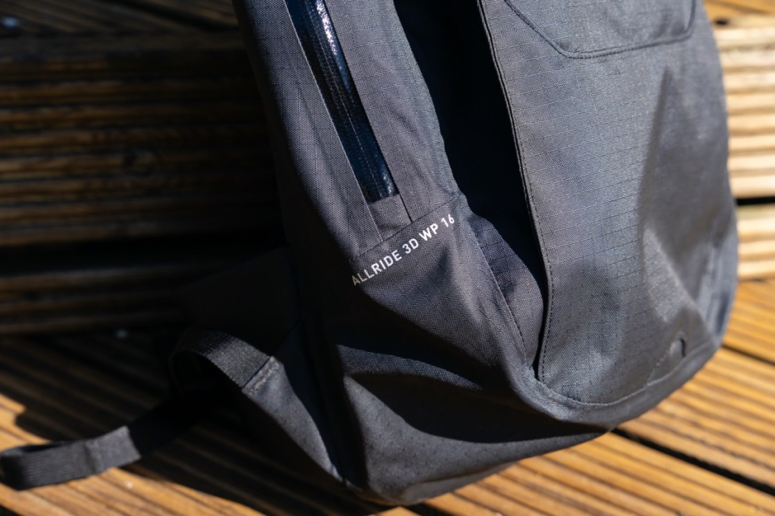 Side view of the Evoc Allride 3D WP16 backpack, showcasing its weatherproof features and zipper.