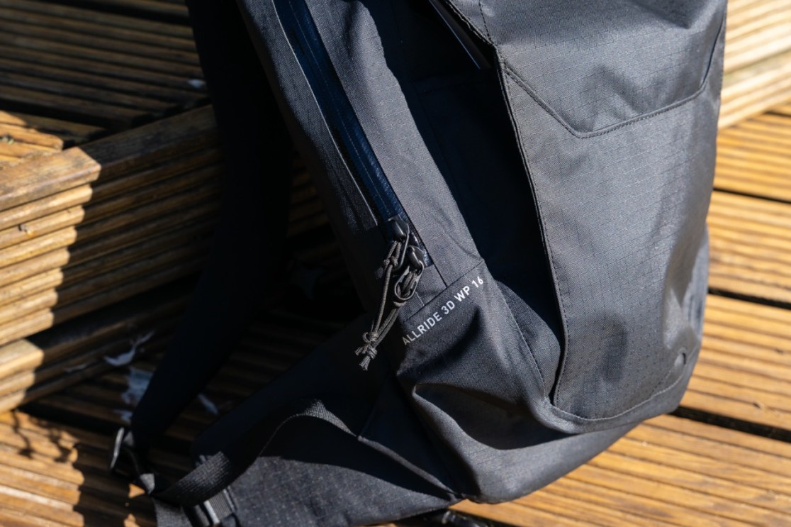Close-up of the side of the Evoc Allride 3D WP16 backpack, showcasing the waterproof zips and textured fabric.