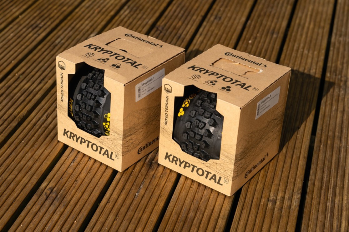 Two boxes of Continental Kryptotal bicycle tires on a wooden surface, showcasing the tire designs and packaging.