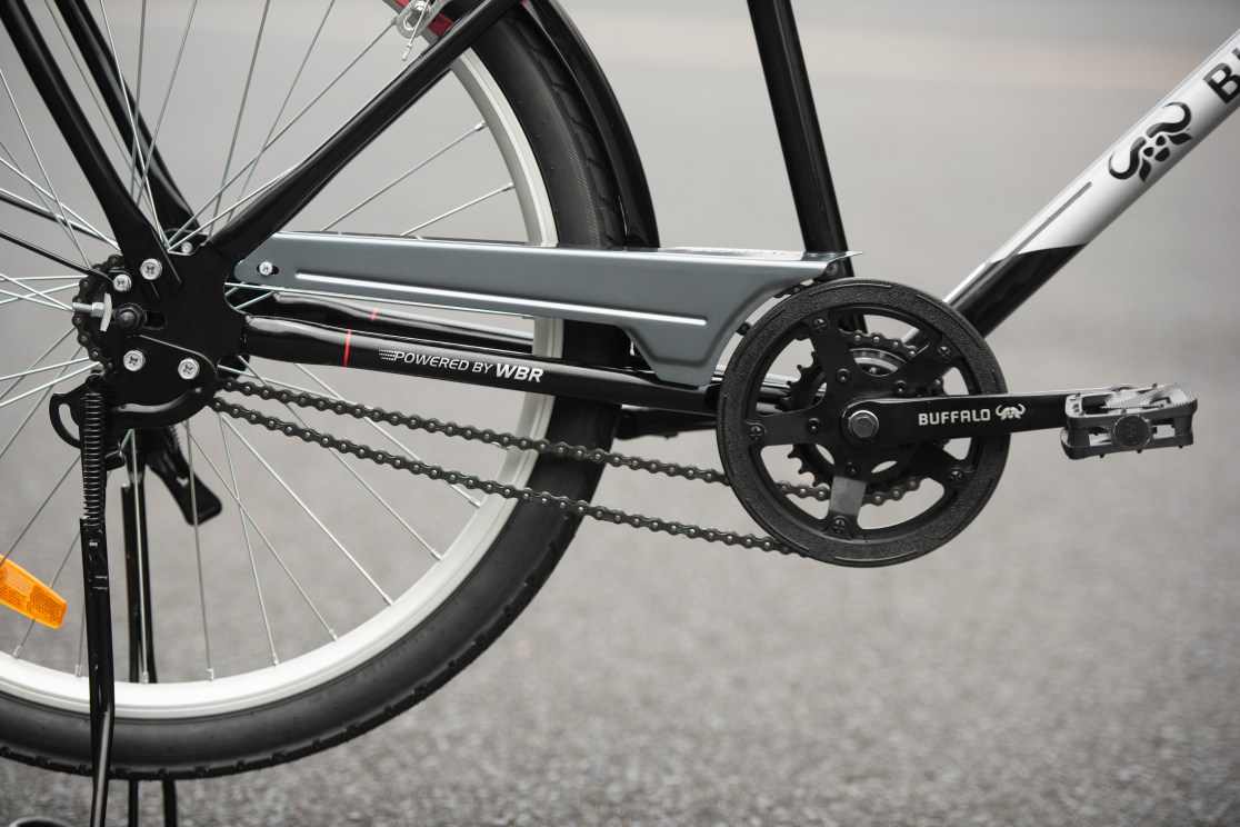 Close-up view of a bicycle's chainring, pedals, and drivetrain components on a smooth surface.