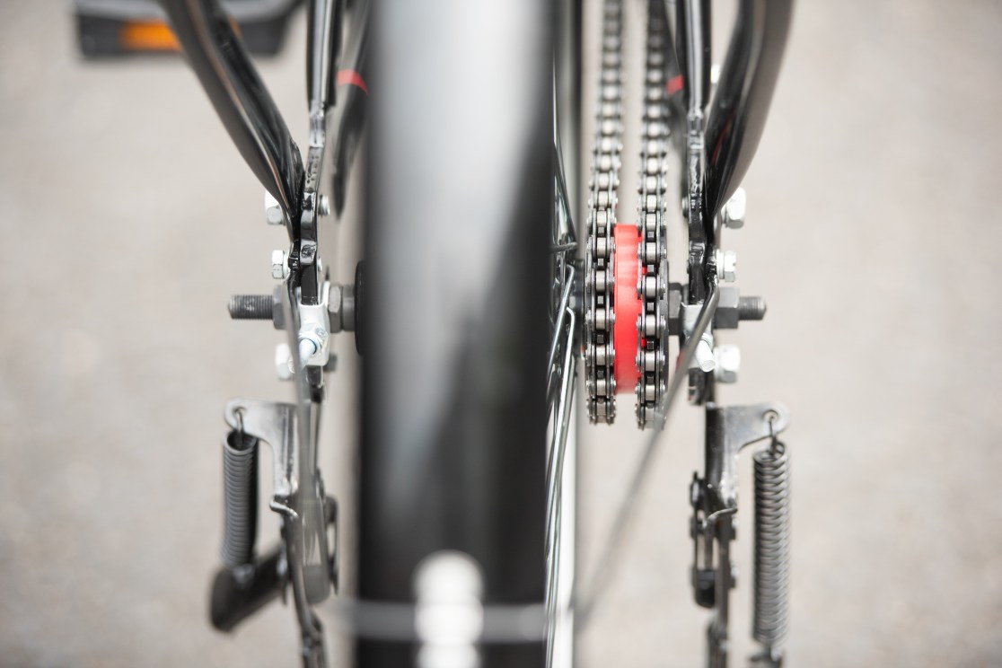 Close-up view of a bicycle's rear gear mechanism, showcasing the chain, red gear, and various components.