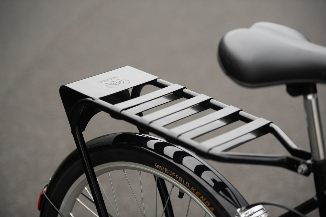 Close-up of a black bicycle rack positioned on the rear of a bike, with part of the saddle visible in the background.