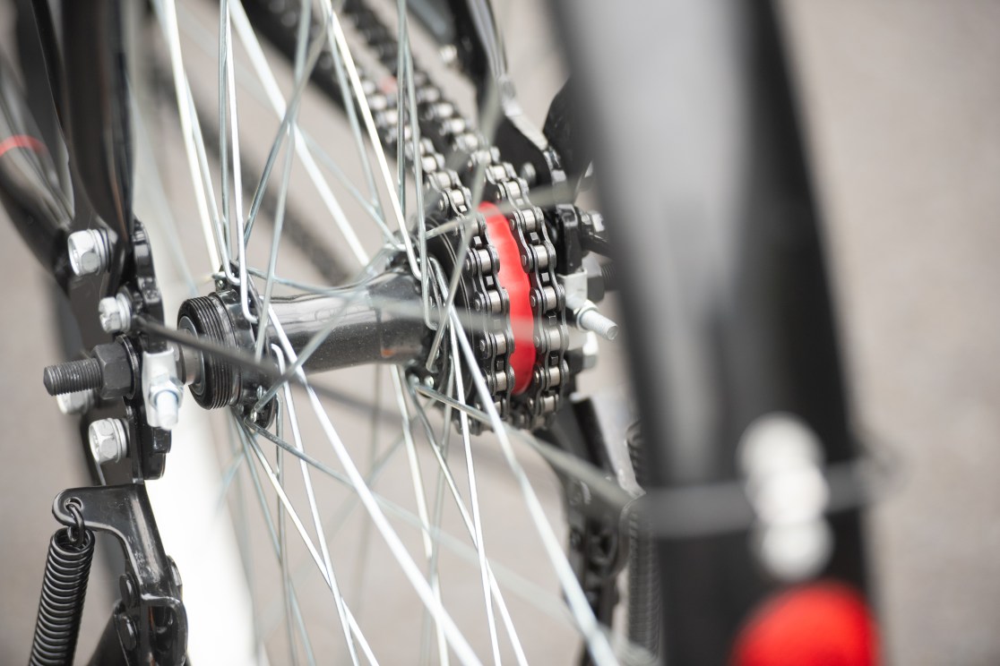 Close-up view of a bicycle's rear wheel hub, showing the chain and gears with a red accent.