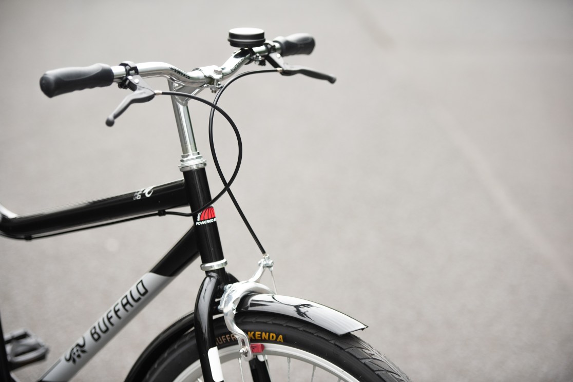 Close-up view of a bicycle's handlebars, featuring a black frame, grips, and a shiny silver brake lever.