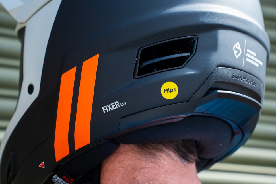Close-up view of the Sweet Protection Fixer Composite 2Vi Mips helmet highlighting its sleek design, orange stripes, and ventilation openings.