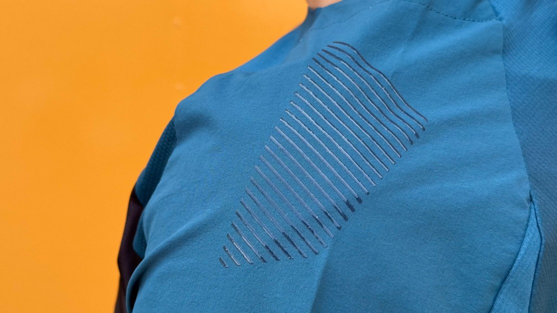 Close-up of a blue sports jersey featuring a textured design on the front, with a bright orange background.