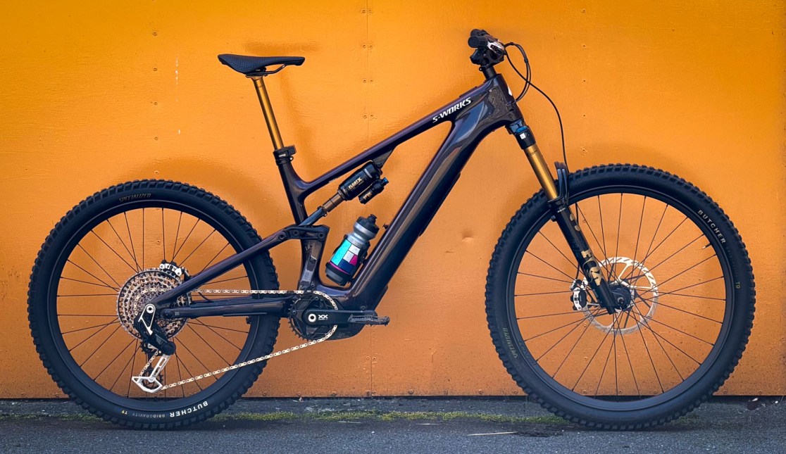 Profile view of a high-end S-Works Turbo Levo 4 Carbon mountain bike against an orange background, showcasing its sleek design and features.