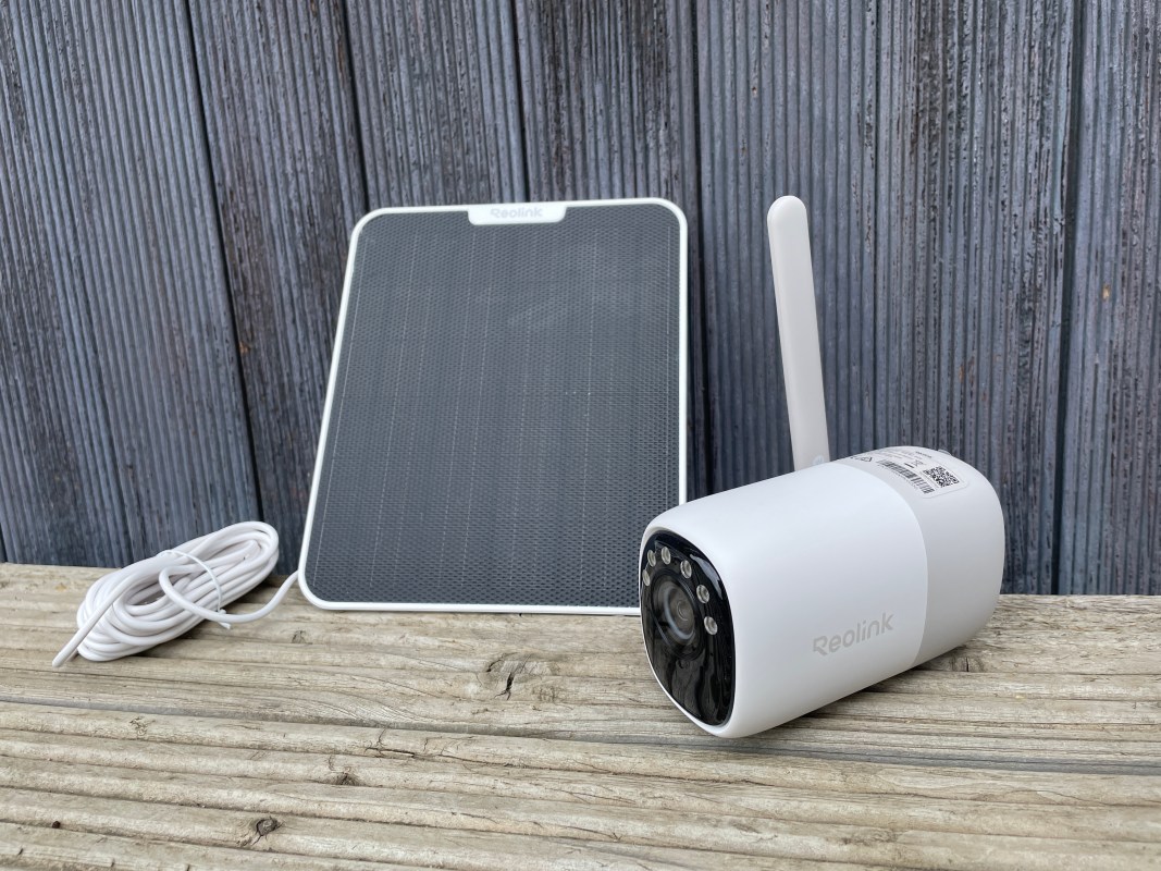 Reolink Altas security camera with a solar panel, power cable, and wooden surface background.