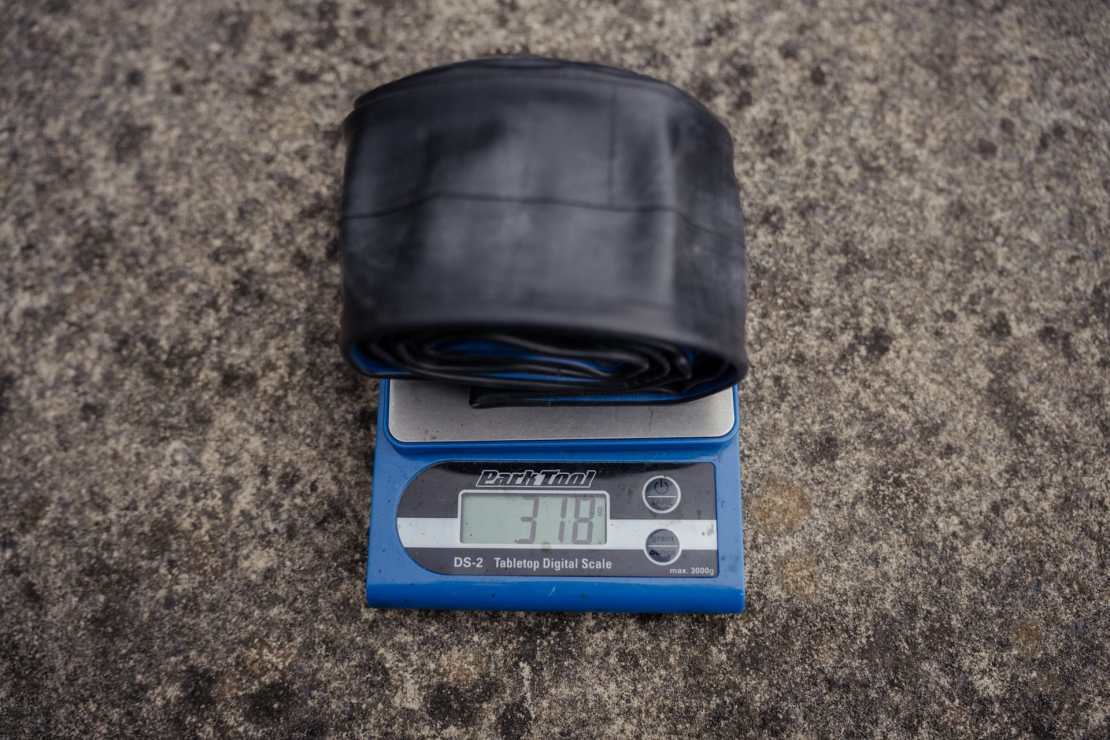 A bicycle inner tube being weighed on a digital scale, displaying a weight of 318 grams.