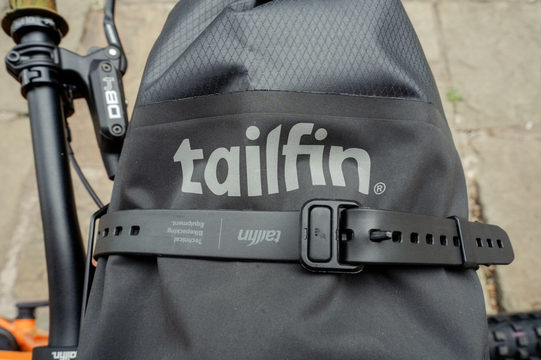 Close-up view of a Tailfin bikepacking accessory featuring the brand logo and use of a securing strap.