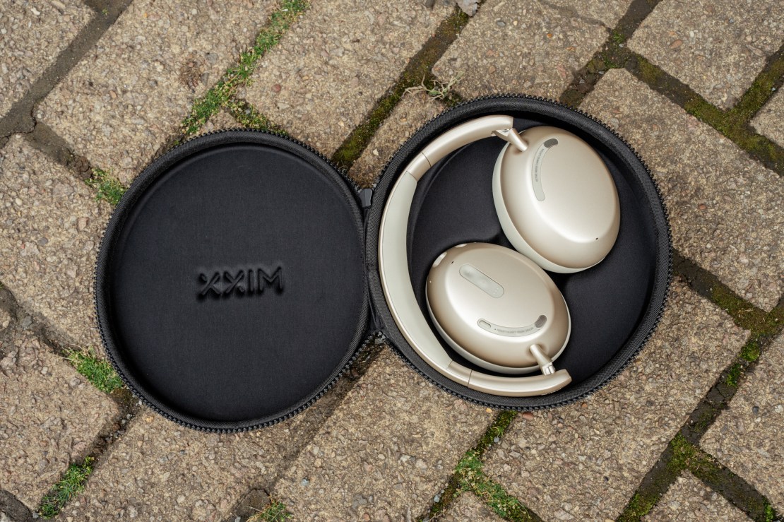 Over-ear headphones stored in a black carrying case, with headphones featuring a gold finish visible inside.