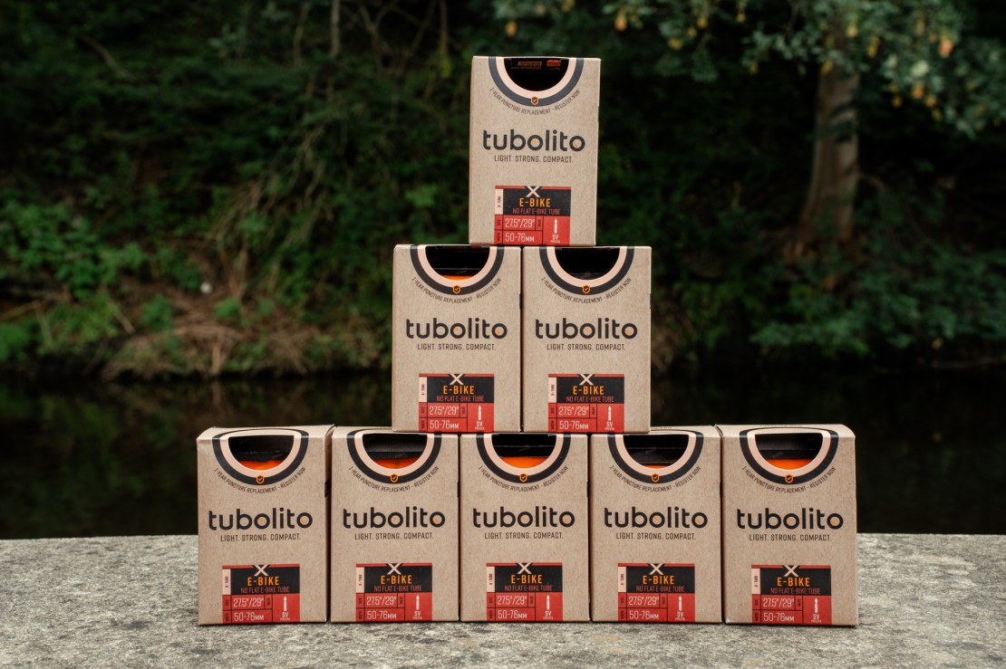 A stack of Tubolito bicycle tubes displayed in a pyramid shape, featuring branding and product information on the packaging.