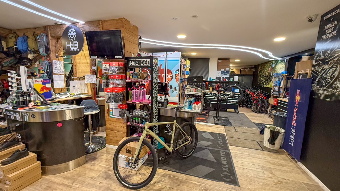 Interior view of The Hub Les Gets bike shop, featuring a variety of biking gear, accessories, and rental bikes on display.