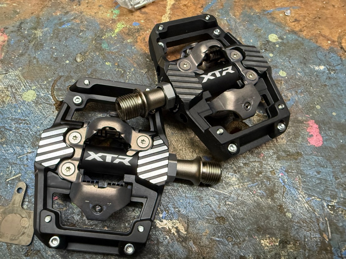 Close-up of Shimano XTR PD-M9220 trail pedals on a workbench, showcasing their design and features.