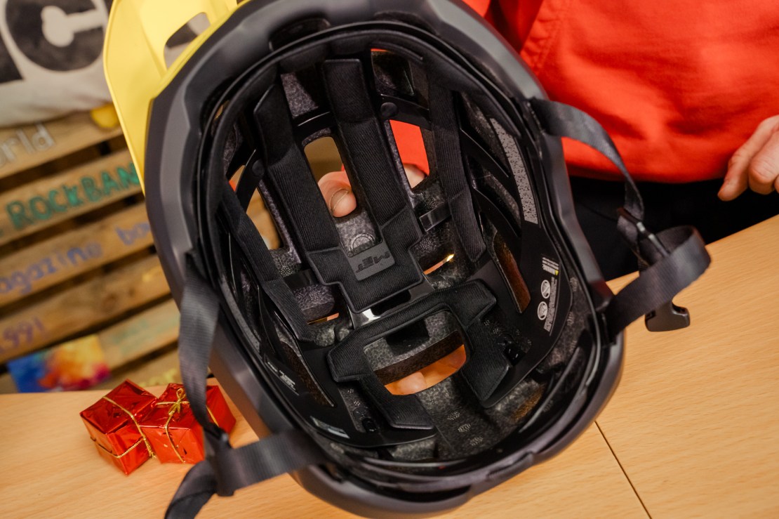 Interior view of a MET Terrae MIPS helmet showing its padding and adjustment straps, with festive red gift boxes in the foreground.
